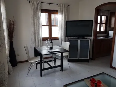 Dining area at Casa Sol y Playa with table for two, flat-screen TV, and kitchen archway